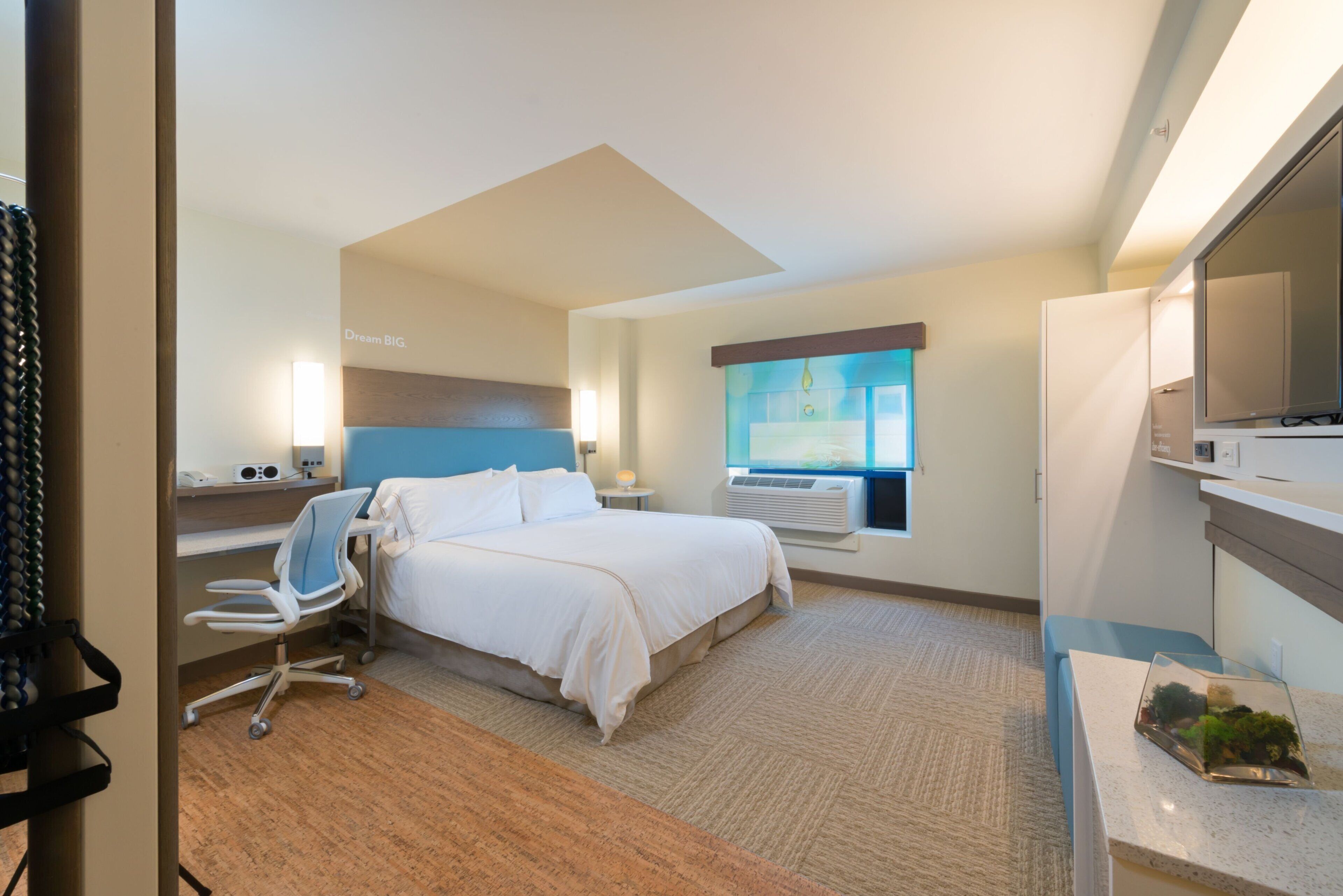Ein Hotelzimmer mit Bett, Schreibtisch, Stuhl, Fernseher und einem Fenster mit Blick.