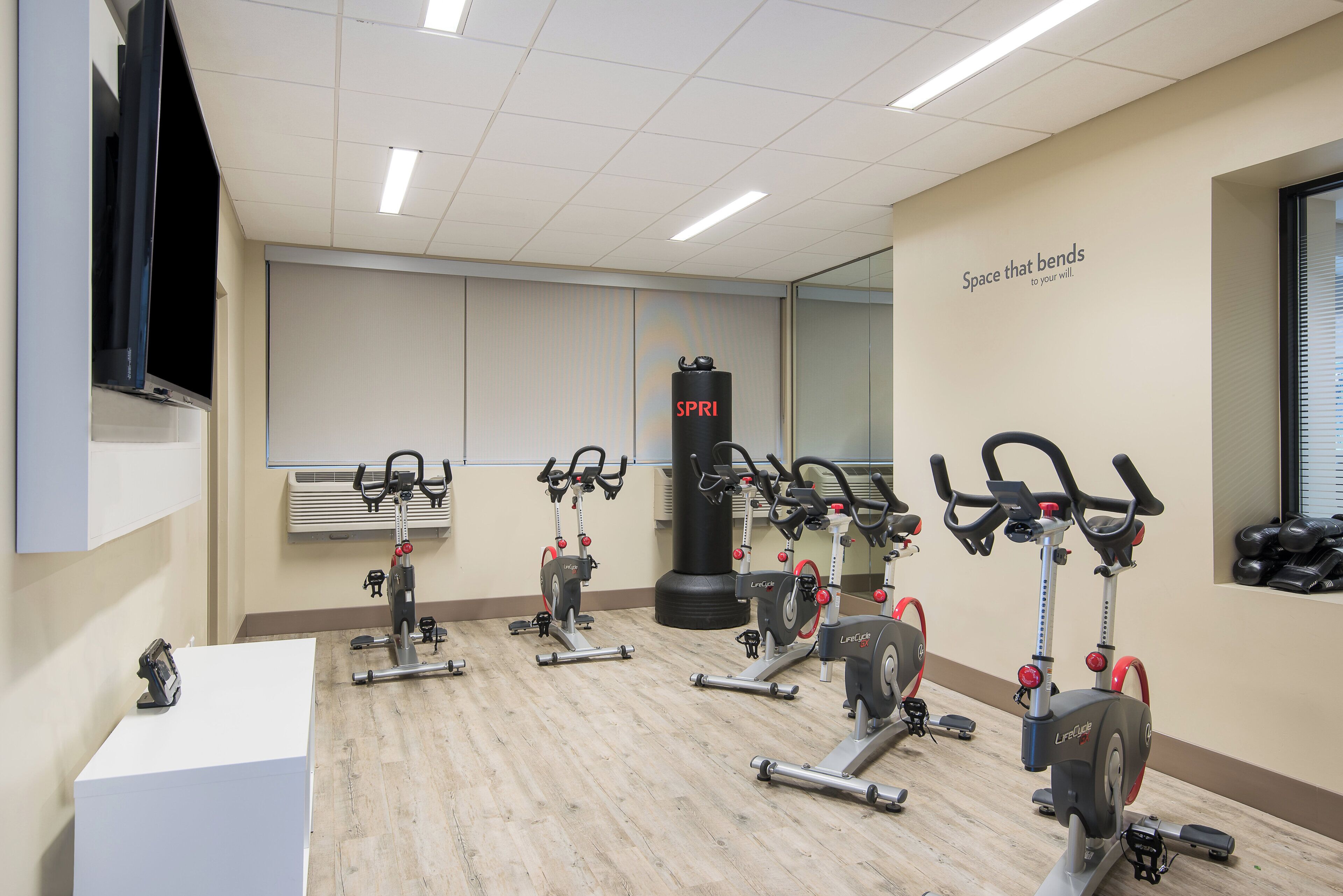 Una palestra con cyclette, un sacco da boxe e una parete con scritte motivazionali.