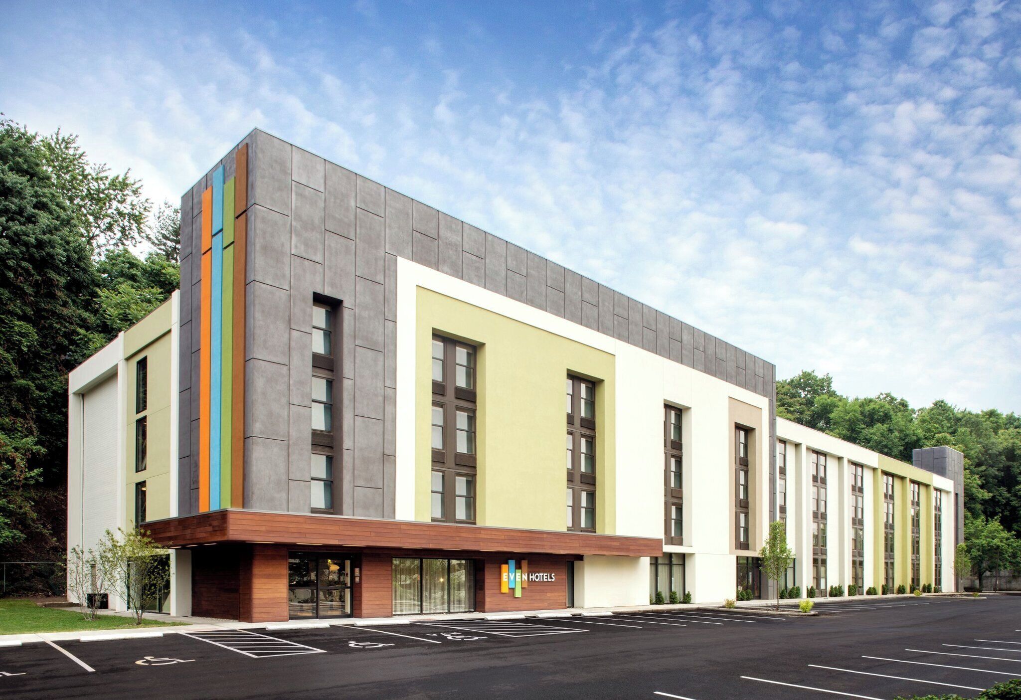 Un hotel moderno con techo plano, ventanas amplias y un estacionamiento al frente.