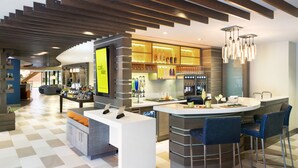 A modern kitchen with a bar area, featuring a large island, bar stools, and a variety of kitchen appliances. - EVEN Hotel Norwalk by IHG (Norwalk)