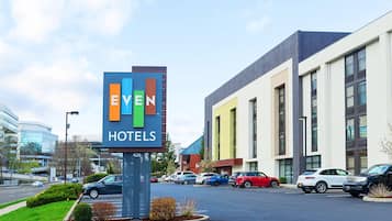 Une enseigne d’hôtel portant le nom « EVEN HOTELS » et un parking où sont garées plusieurs voitures.