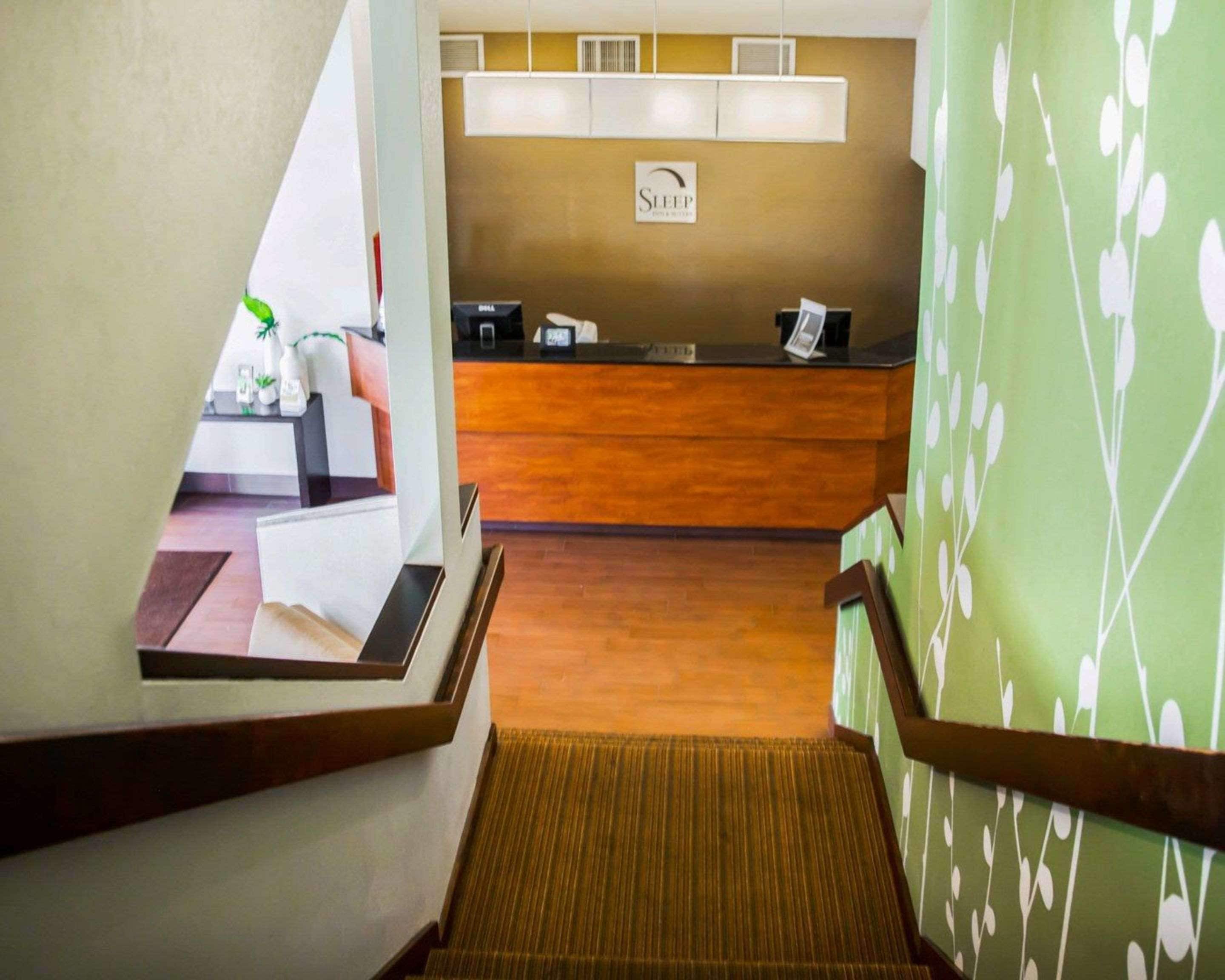 A hotel reception area with a wooden reception desk, a sign that reads "SLEEP," and a reception counter.