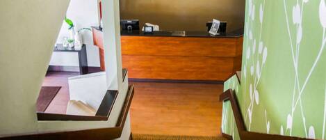 A hotel reception area with a wooden reception desk, a sign that reads "SLEEP," and a reception counter.