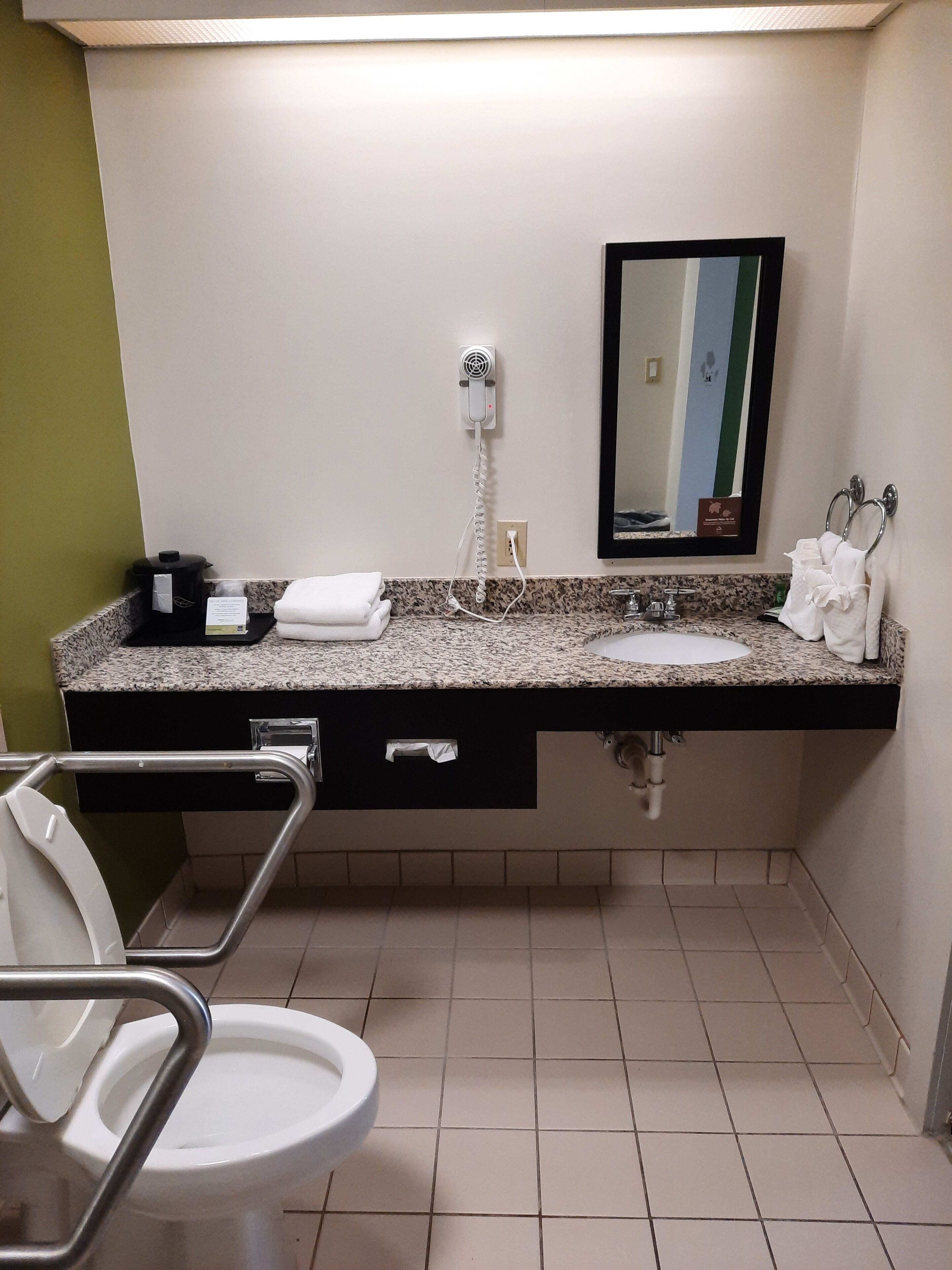 Un baño con lavamanos, espejo, toallero y retrete.