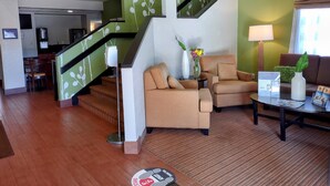 Eine Hotelhalle mit Treppe, Sitzgelegenheit und Rezeption.