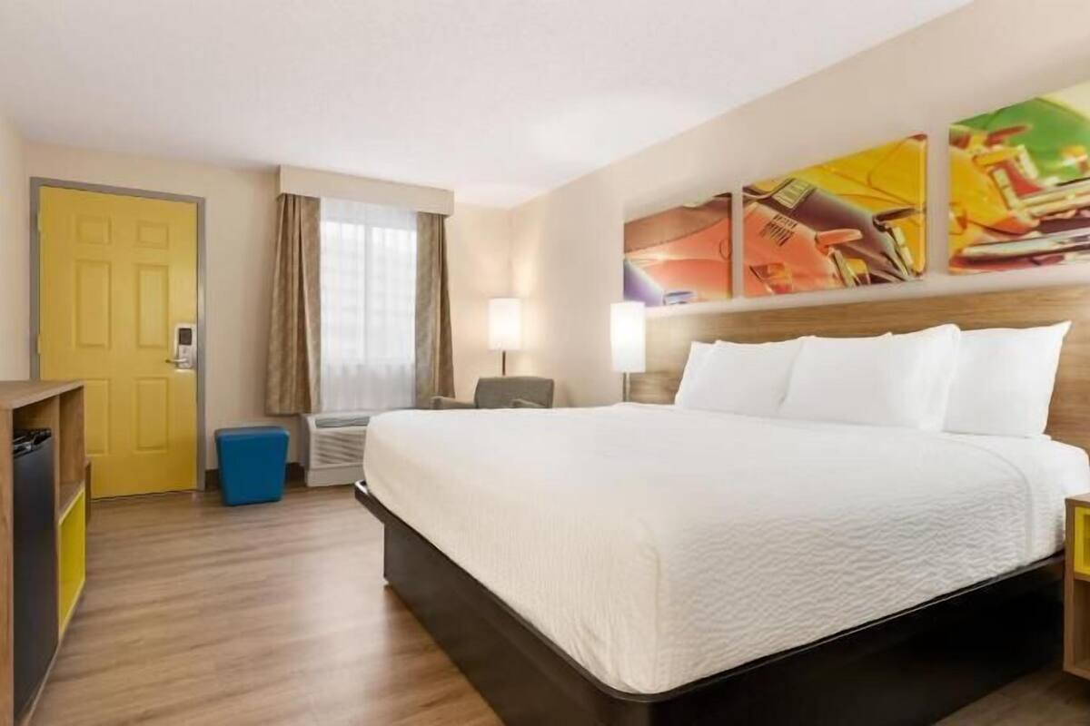 A hotel room with a bed, bedside tables, a TV, a wardrobe, and a window with curtains.