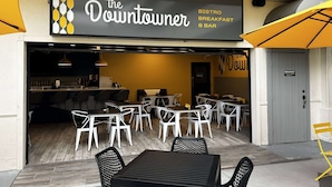 Ein Außenbereich mit Tischen und Stühlen, ein Schild für das Restaurant 'The Downtowner' und eine Tür zum Innenbereich.