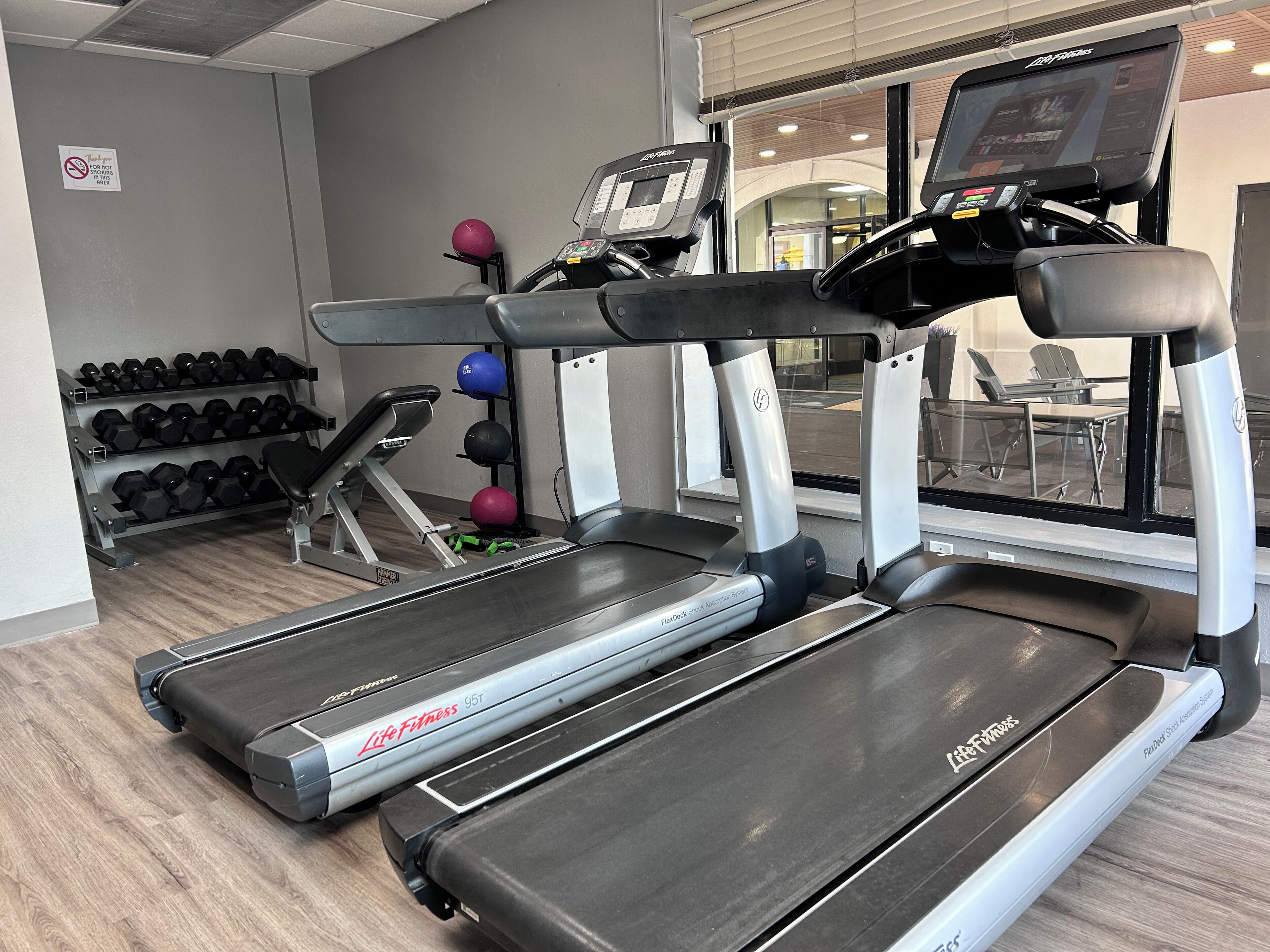 A gym with treadmills, dumbbells, and exercise balls.