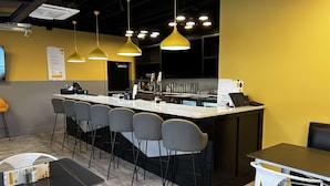 Eine moderne Bar mit einer zentralen Theke, Barhocker und Pendelleuchten.