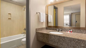 Un baño moderno con lavamanos de granito, un espejo grande y una bañera.