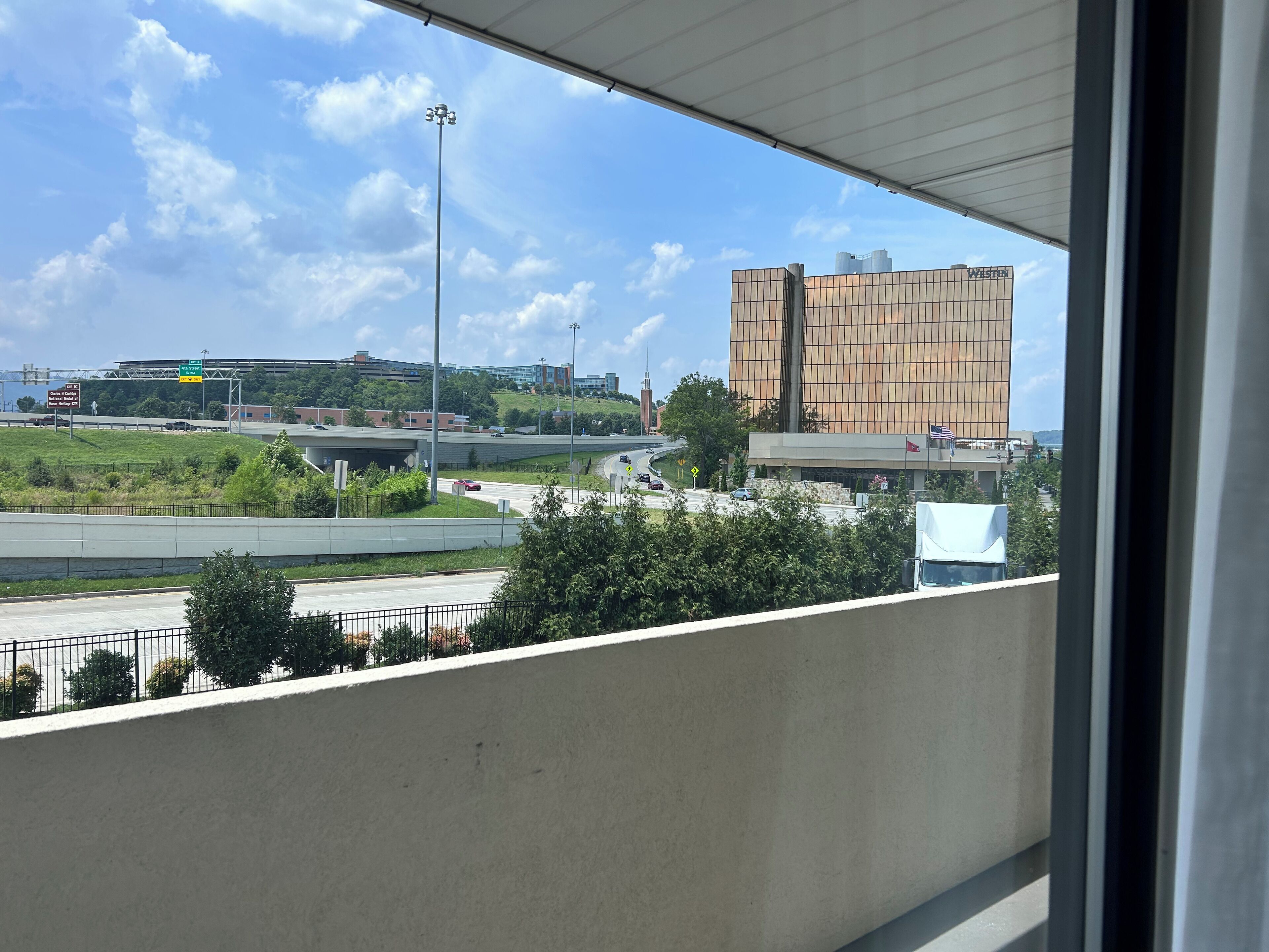 Uitzicht vanaf een balkon op een snelweg, met een modern gebouw op de achtergrond.
