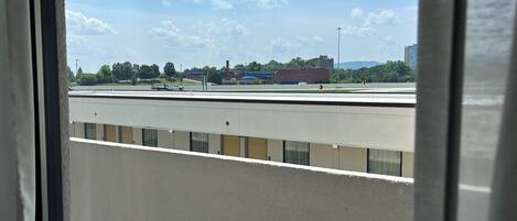 A view from a window overlooking a road with vehicles, buildings, and a clear sky.
