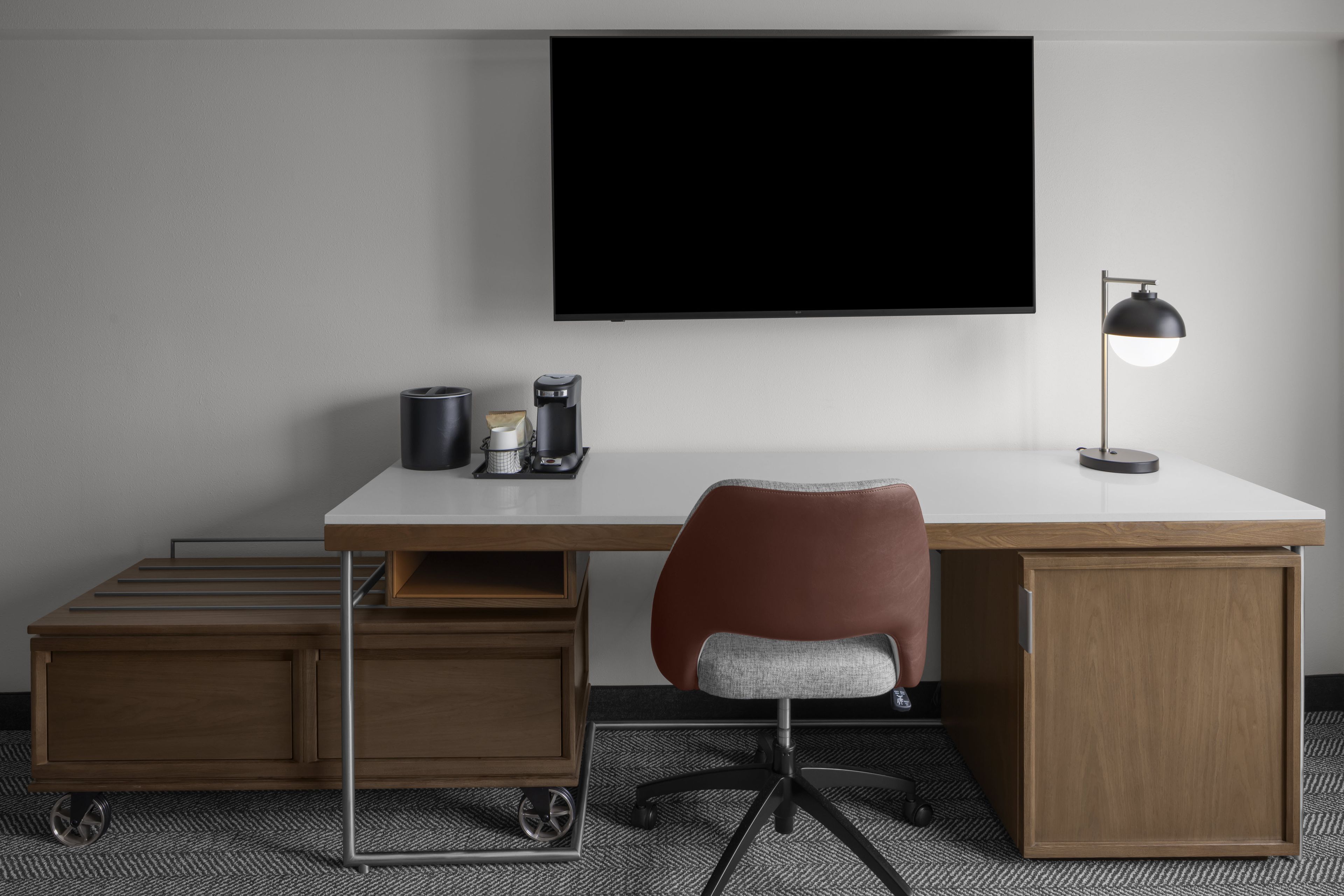 Un bureau moderne doté d’un écran plat, d’une lampe de bureau et d’une machine à café.