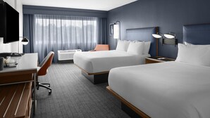 Ein Hotelzimmer mit Bett, Schreibtisch, Stuhl und Fernseher.
