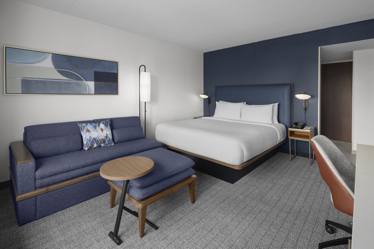 Une chambre d’hôtel avec un lit, un canapé, une petite table et une chaise.