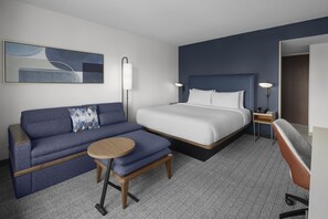 Une chambre d’hôtel avec un lit, un canapé, une petite table et une chaise.