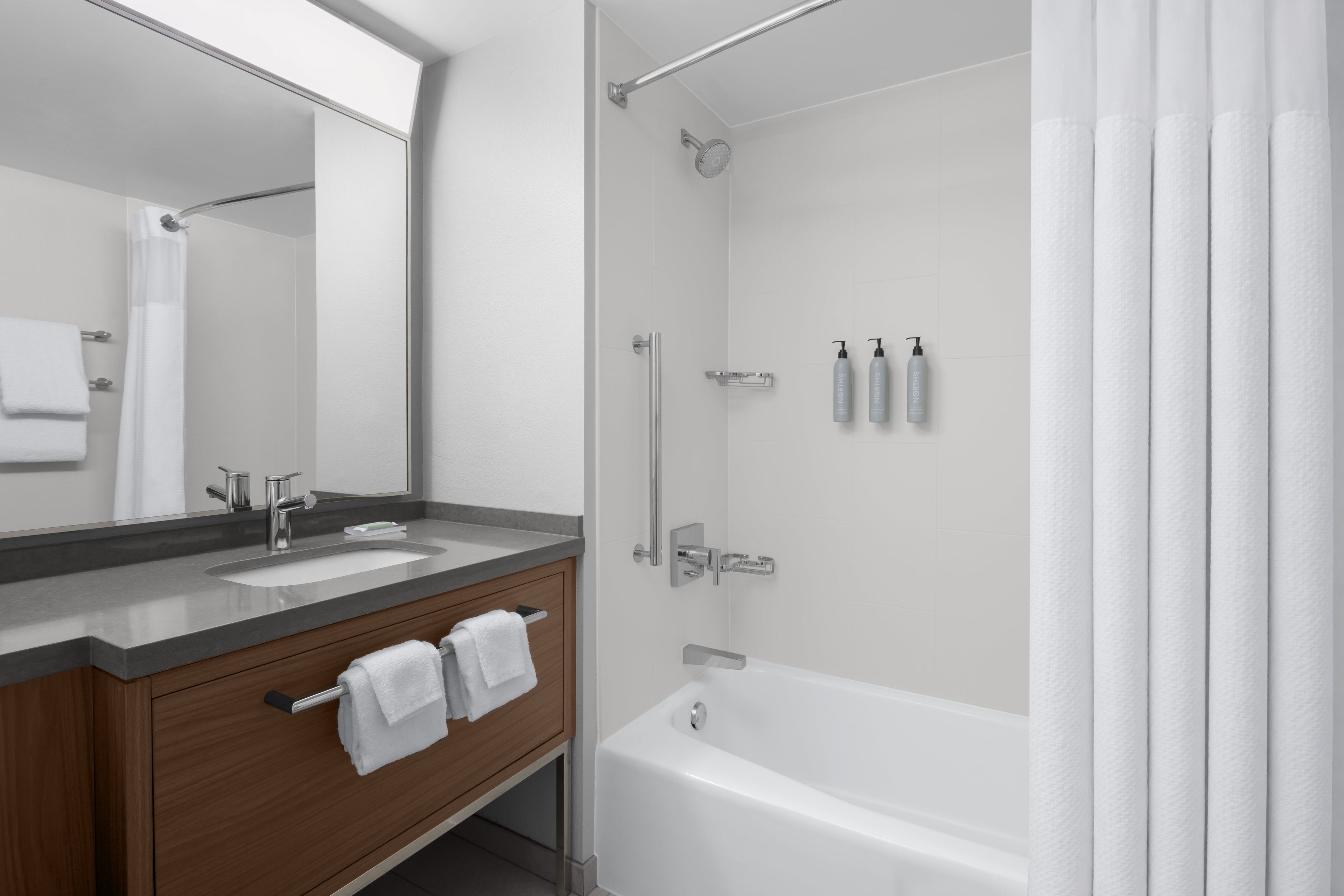 A modern bathroom with a double sink vanity, a bathtub, and a shower.