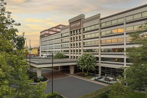 A multi-story hotel with a flat facade, large windows, and a parking area with a covered walkway. - Courtyard by Marriott Lyndhurst Meadowlands (Lyndhurst)