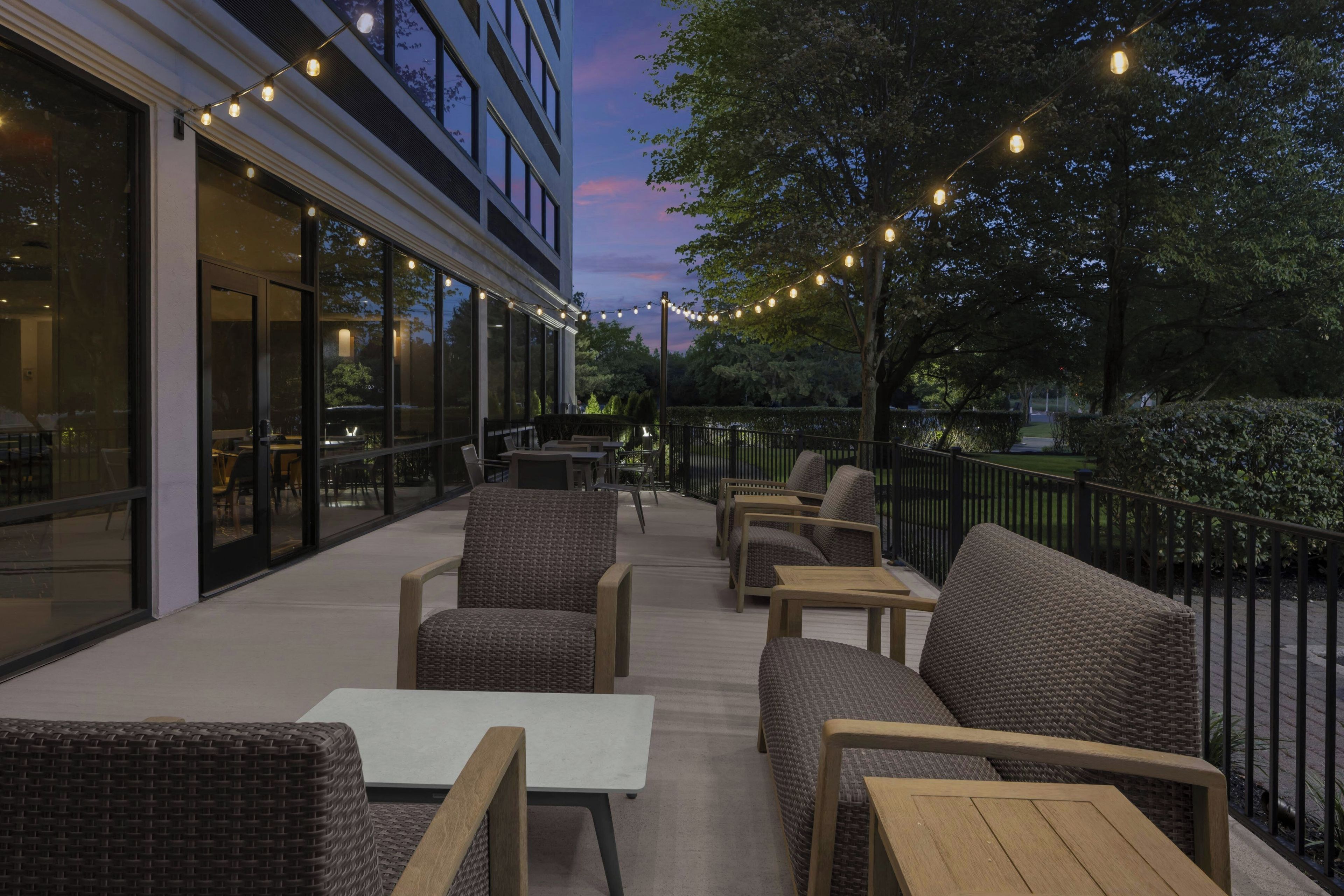 An outdoor seating area with wicker furniture and string lights.