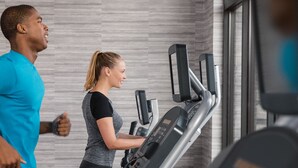 Une salle de sport avec des tapis de course et une personne qui court.