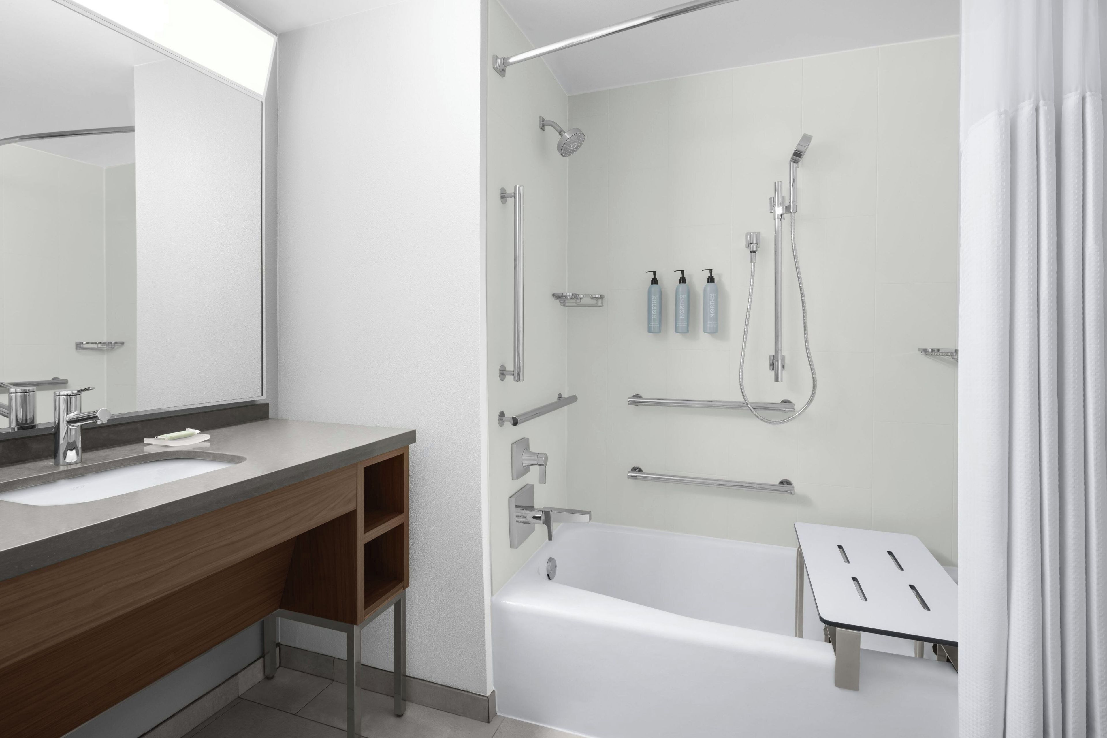 A modern bathroom with a bathtub, a shower, a vanity with a mirror, and a toilet.