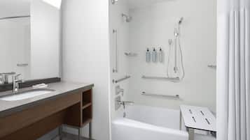 A modern bathroom with a bathtub, a shower, a vanity with a mirror, and a toilet.