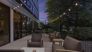 Un espace extérieur aménagé avec des meubles en osier et des guirlandes lumineuses.