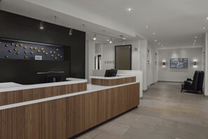 Un comptoir d’accueil moderne avec un revêtement en bois, un écran numérique et une enseigne murale sur laquelle on peut lire « CRATE ».