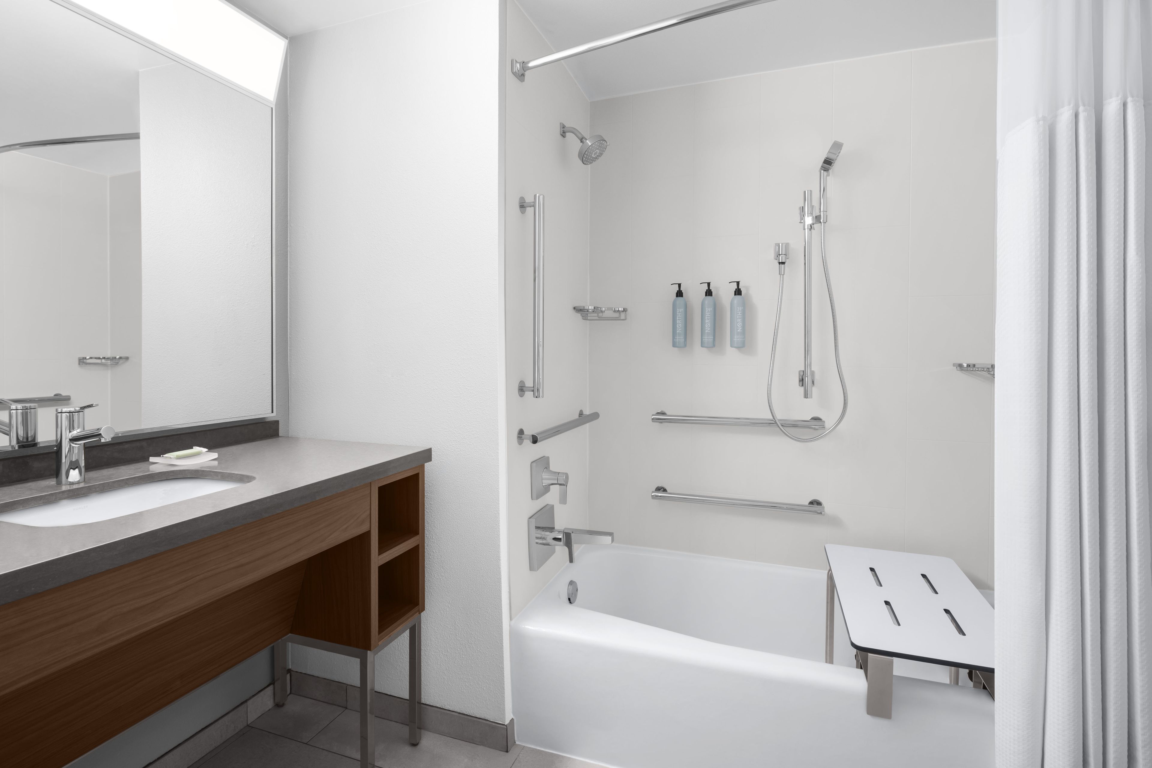 Un baño moderno con una bañera, ducha, tocador con espejo y un inodoro.