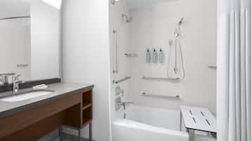 A modern bathroom with a bathtub, a shower, a vanity with a mirror, and a toilet.