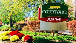 Une enseigne Courtyard Marriott, entourée de parterres fleuris aux couleurs vives et de verdure.
