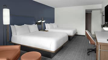 A hotel room with a large bed, two bedside tables, a desk, a chair, and a mirror.
