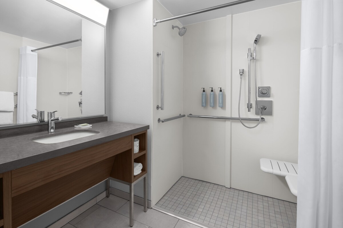 Une salle de bain moderne dotée d’un meuble-lavabo à deux vasques, d’une douche à l’italienne avec un pommeau de douche à main et de toilettes séparées.