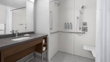 A modern bathroom with a dual sink vanity, a walk-in shower with a handheld showerhead, and a separate toilet area.