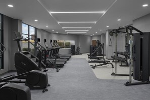 Ein modernes Fitnessstudio mit Laufbändern, Kraftgeräten und Kurzhanteln.