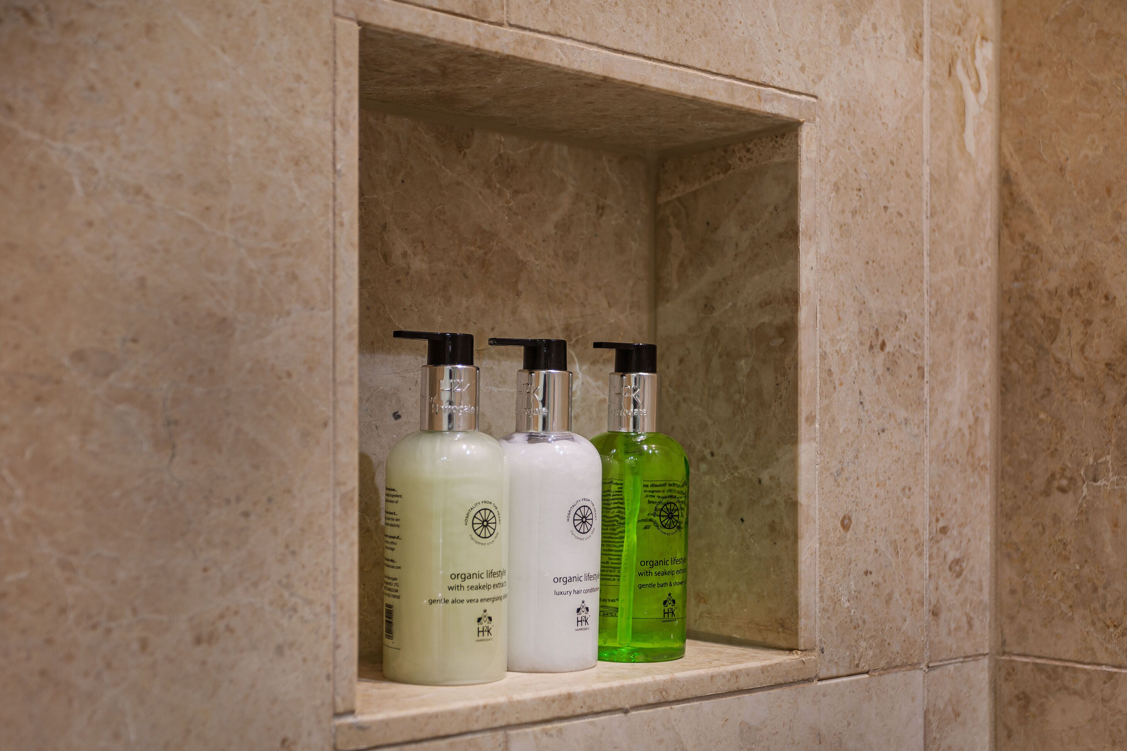 A shelf with three bottles of skincare products in a bathroom setting.
