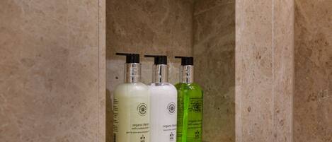 A shelf with three bottles of skincare products in a bathroom setting.