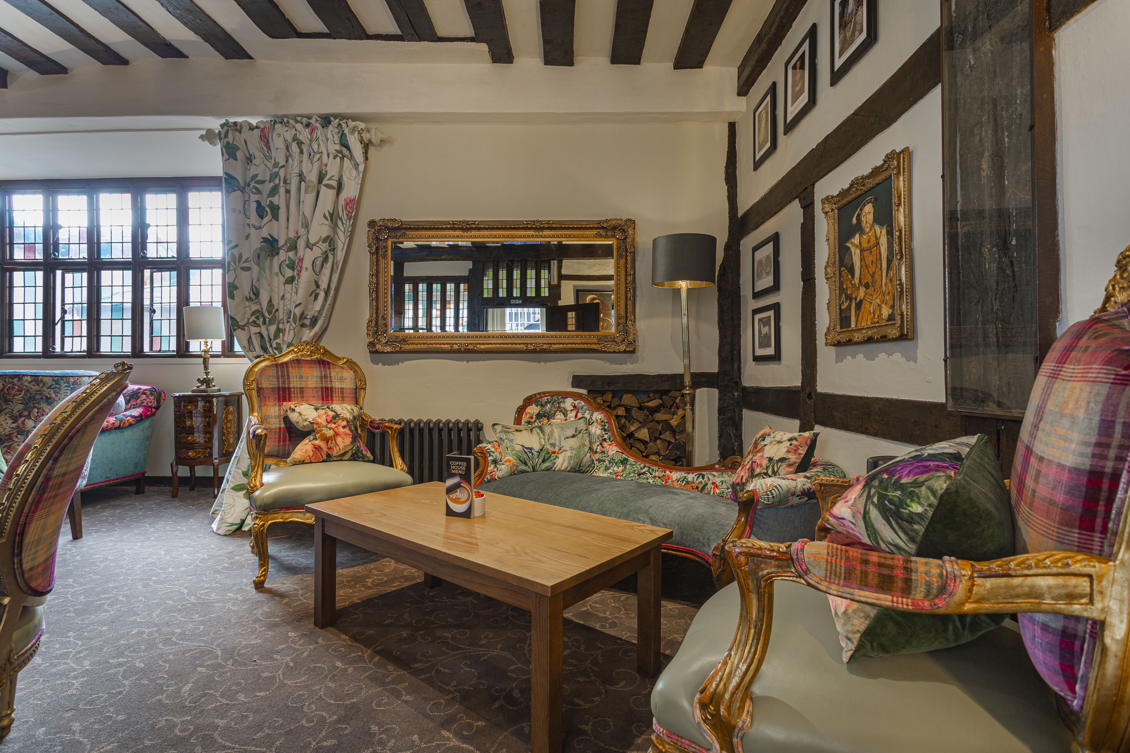 Ein traditionell eingerichteter Raum mit Holztisch, floralen Sofas und einem großen Spiegel.