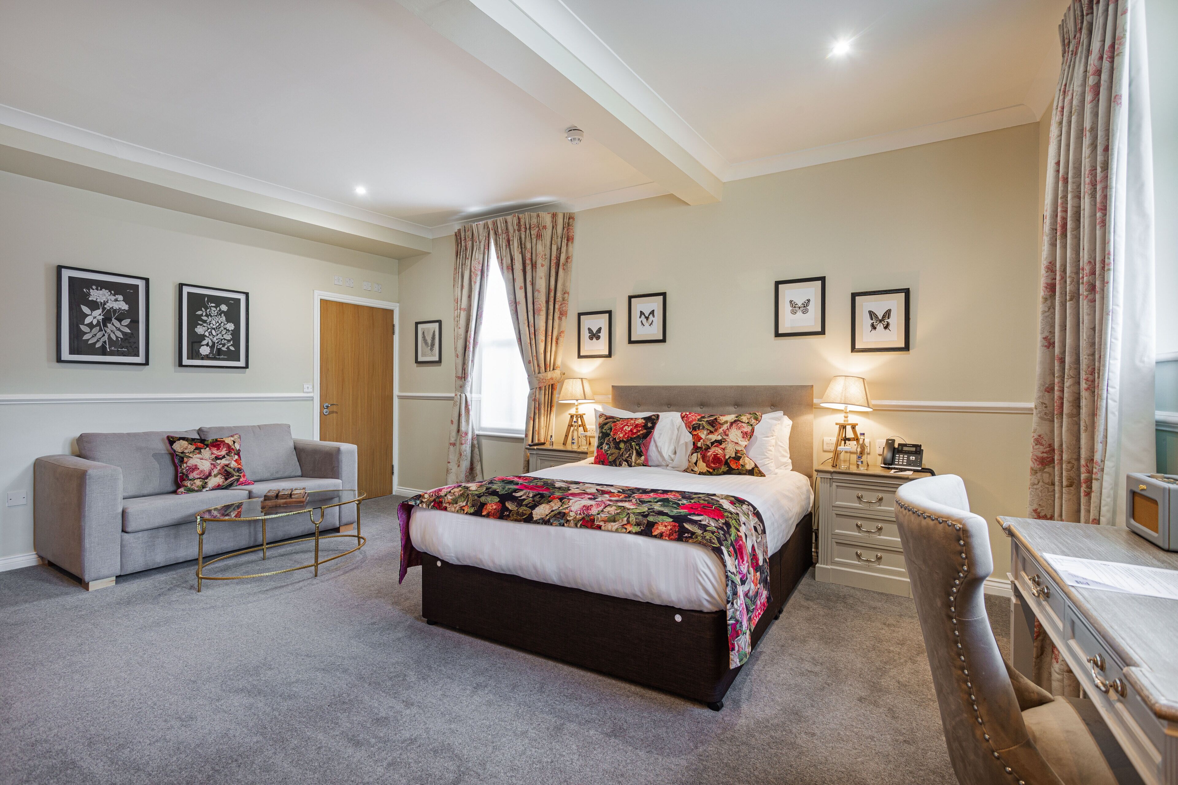 A bedroom with a bed, a sofa, a desk, and a chair.