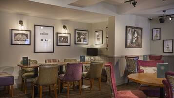 Un comedor con una mesa redonda y sillas, cuadros en las paredes y suelo alfombrado.