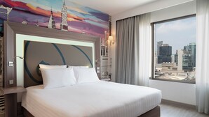 A modern hotel room with a large bed, a cityscape view, and a colorful mural on the wall. - Novotel Bangkok On Siam Square (Bangkok)