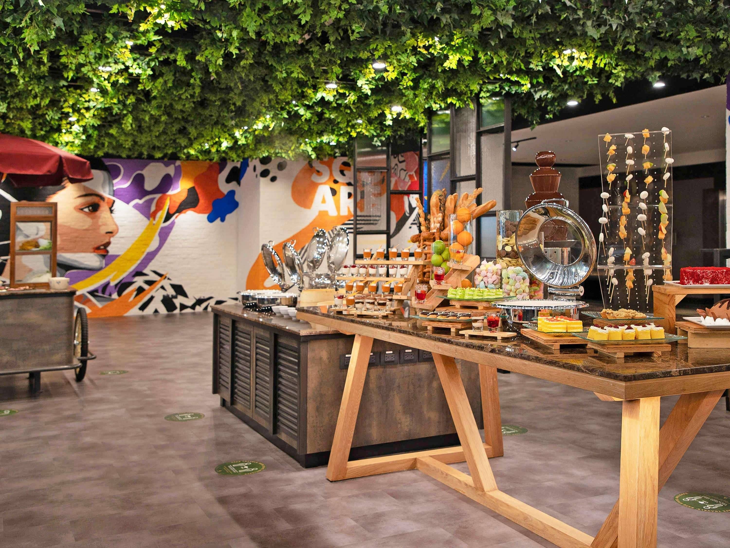 A buffet table with various food items and a mural in the background.