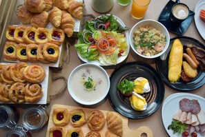 Indulge in a diverse breakfast spread featuring pastries, salads, eggs, sausages, and more.