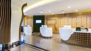 Una moderna zona de recepción con dos mostradores blancos, una pantalla digital y un panel de pared de madera.