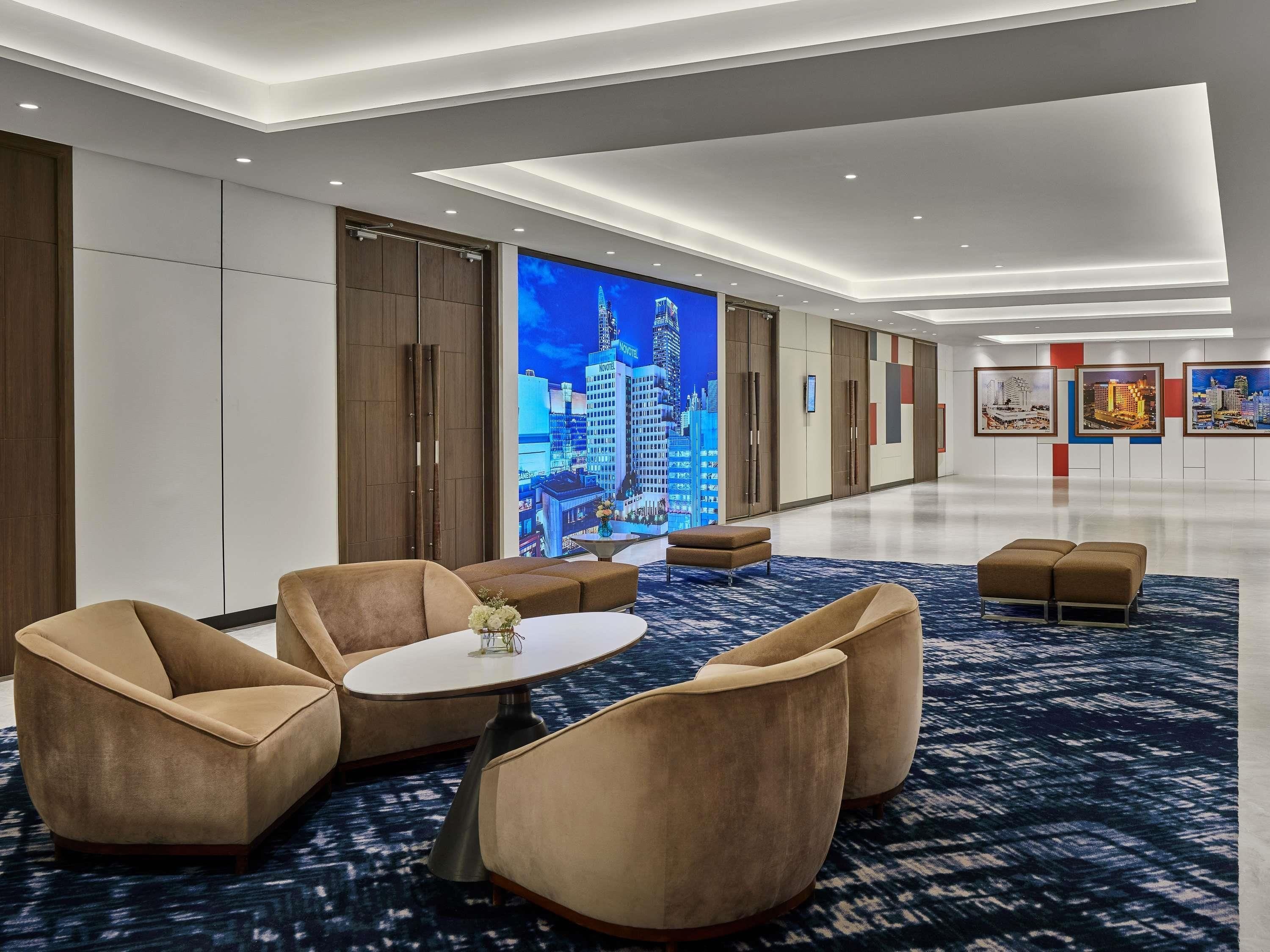 A modern hotel lobby with a large digital screen displaying a cityscape, comfortable seating, and a clean, well-lit interior.