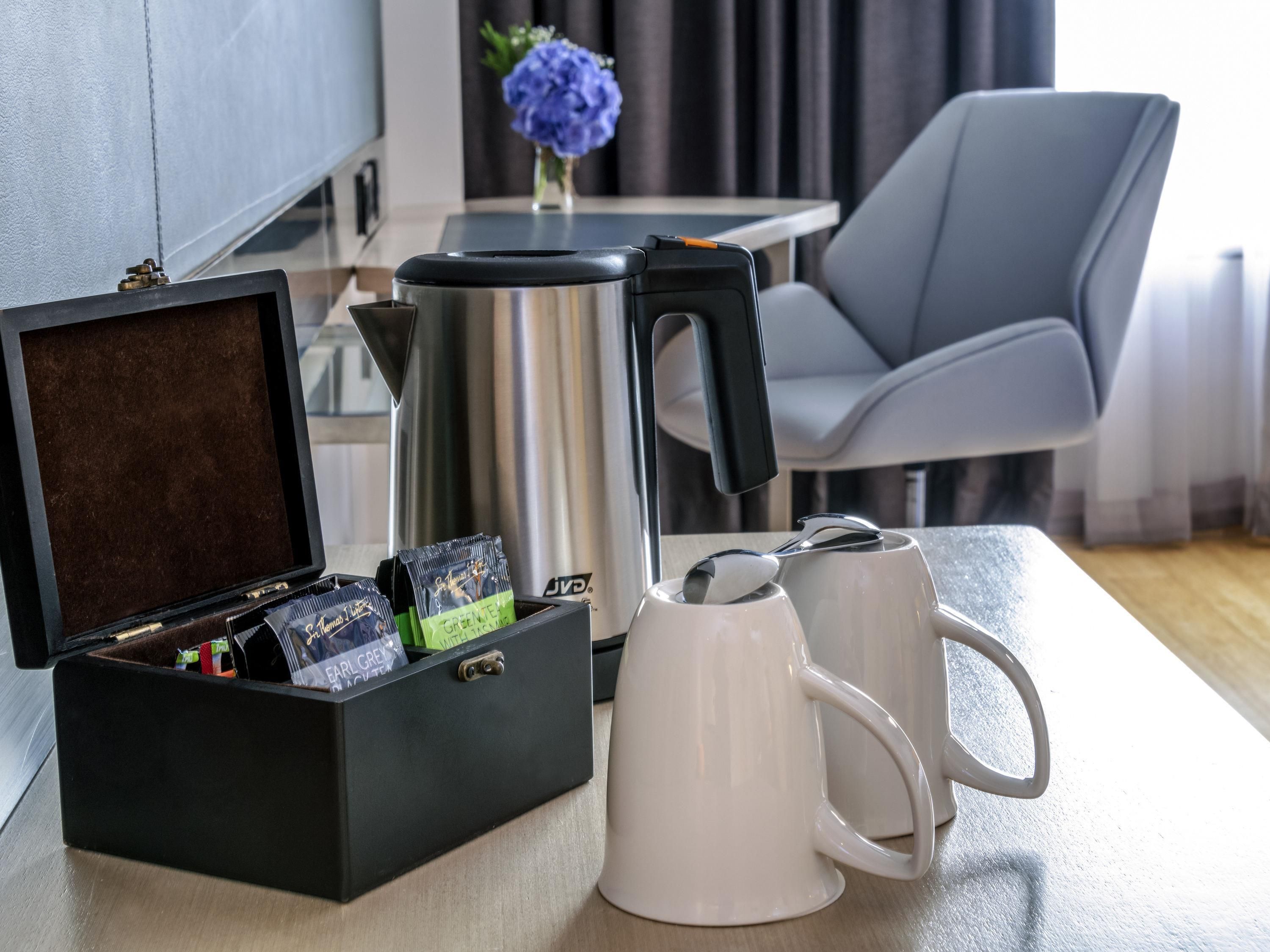 Eine Kaffeestation mit einer Kaffeemaschine, zwei weißen Tassen und einer Packung Kaffee.