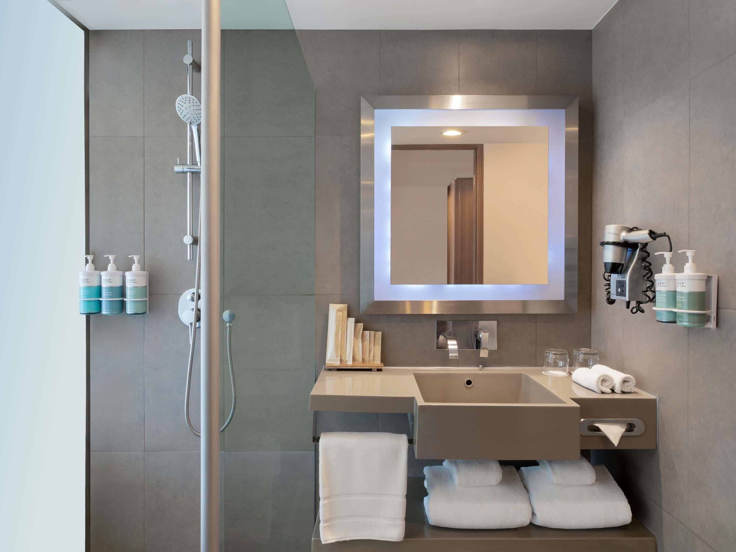 Un bagno moderno con doccia, lavandino, specchio e articoli da toilette.