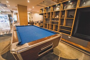 A pool table in a well-lit room with a wooden cabinet displaying various decorative items. - Novotel Bangkok On Siam Square (Bangkok)