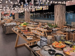 Un buffet proposant différents stands de nourriture, notamment des sushis et des fruits de mer.