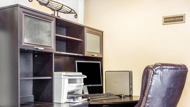A business center with a desk, computer, printer, and leather chair.